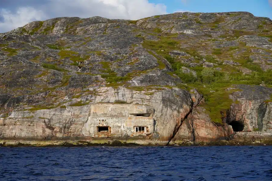 Blick vom Boot auf eine Torpedobatterie aus dem Zweiten Weltkrieg bei Kirkenes in Nordnorwegen
