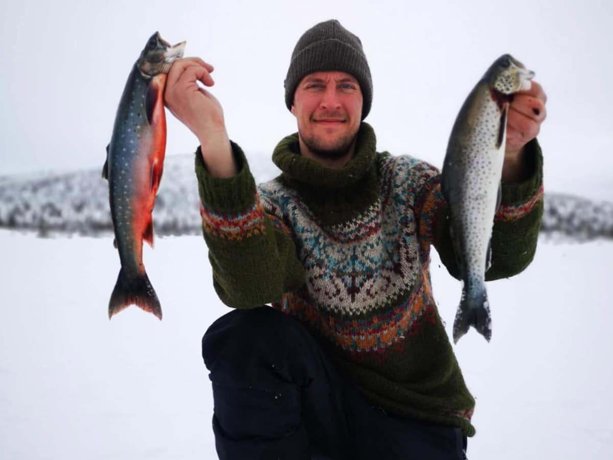 Guide holding fish after successful ice fishing trip near Kirkenes