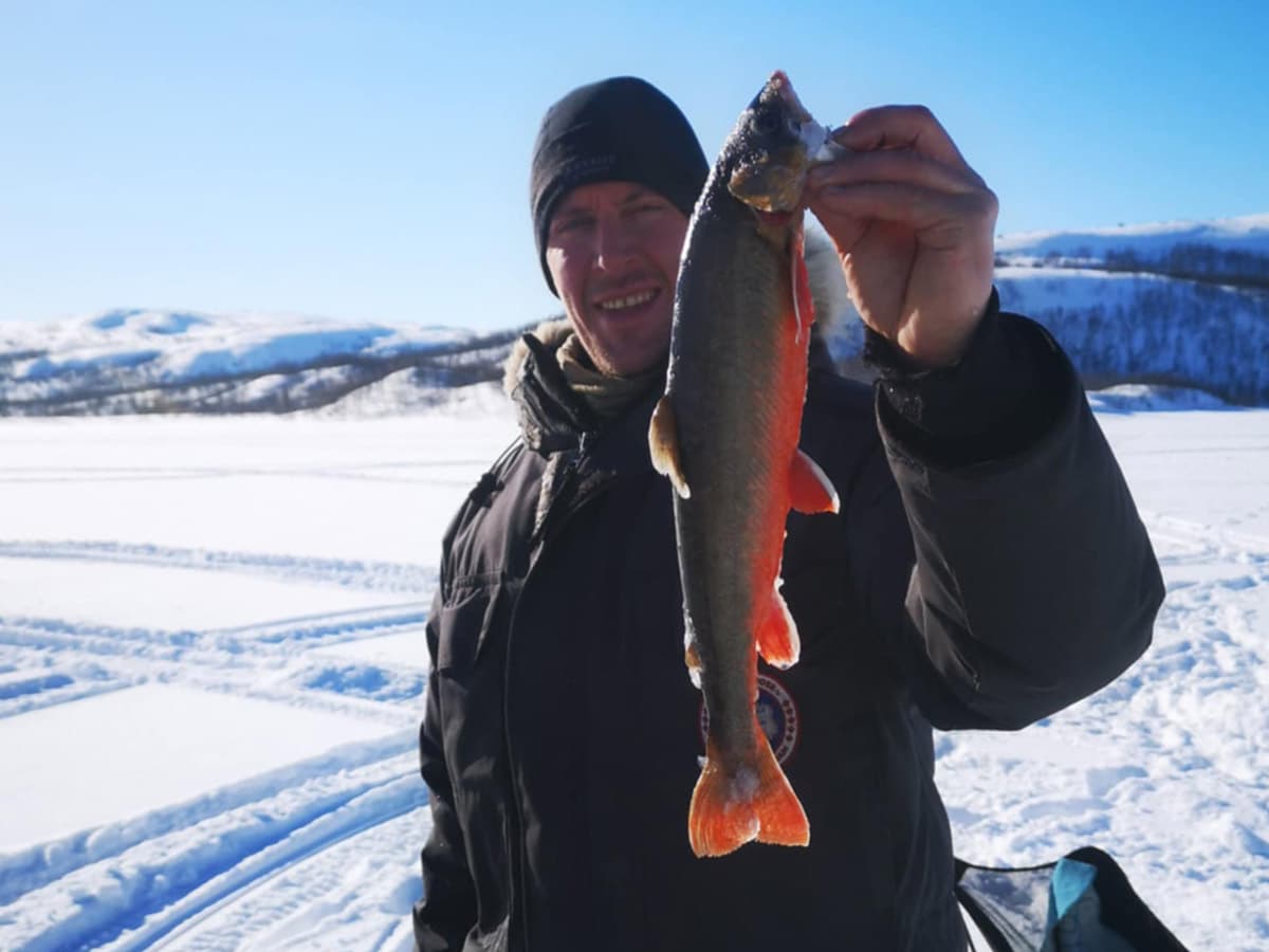 Man holding up a fish on a sunny winter day