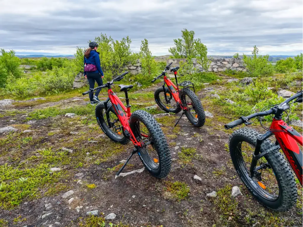 E-fatbikes parked beside historic WWII bunker ruins during a guided e-fatbike tour near Kirkenes, Northern Norway, overlooking the surrounding Arctic landscape.