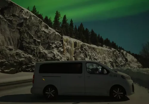 Elektrischer Minivan in der arktischen Natur geparkt, um die Nordlichter zu sehen