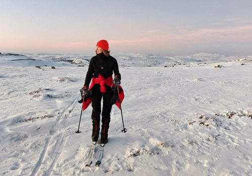 Happy woman skiing around Kirkenes sunset