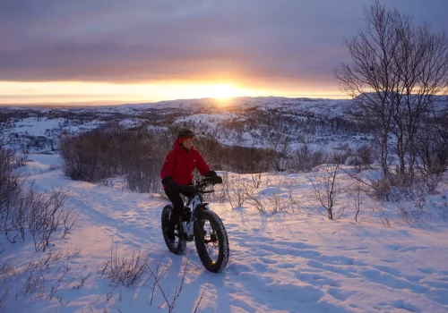 Woman fatbiking through snowy trails around Kirkenes