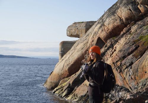 Woman standing close to the WWII torpedo battery at Bøkfjord