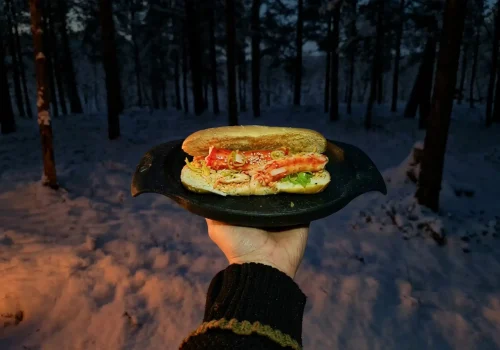 King crab roll served outdoors in a snowy forest near Kirkenes on a winter evening.