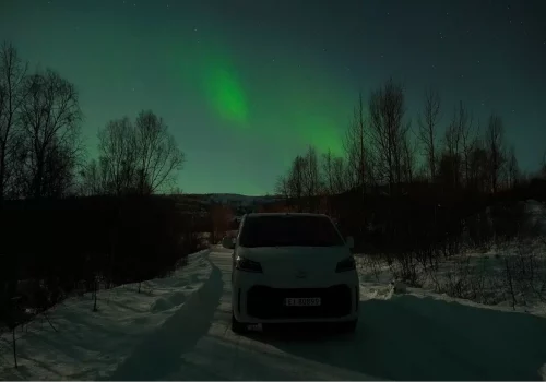 Electric minivan parked in Arctic nature to see the Northern Lights